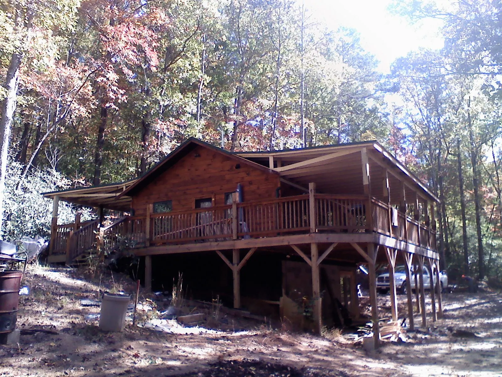 Log cabin with a wraparound porch and metal roof in the fall in Tigrett