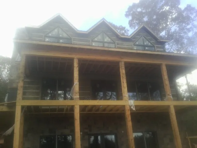 Dormers and porch framing on a large log home under construction — Roof Coating work by our crew in Tigrett