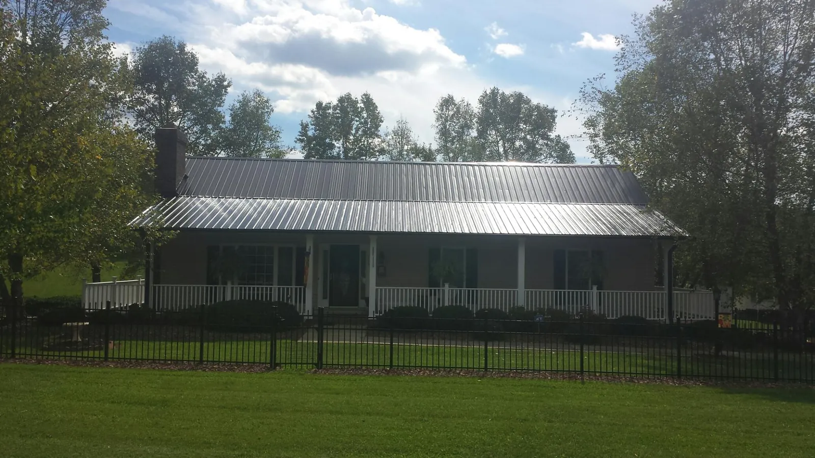 Gray metal roof on a brick ranch with a full width front porch — Gutter Guard Installation work by our crew in Tigrett