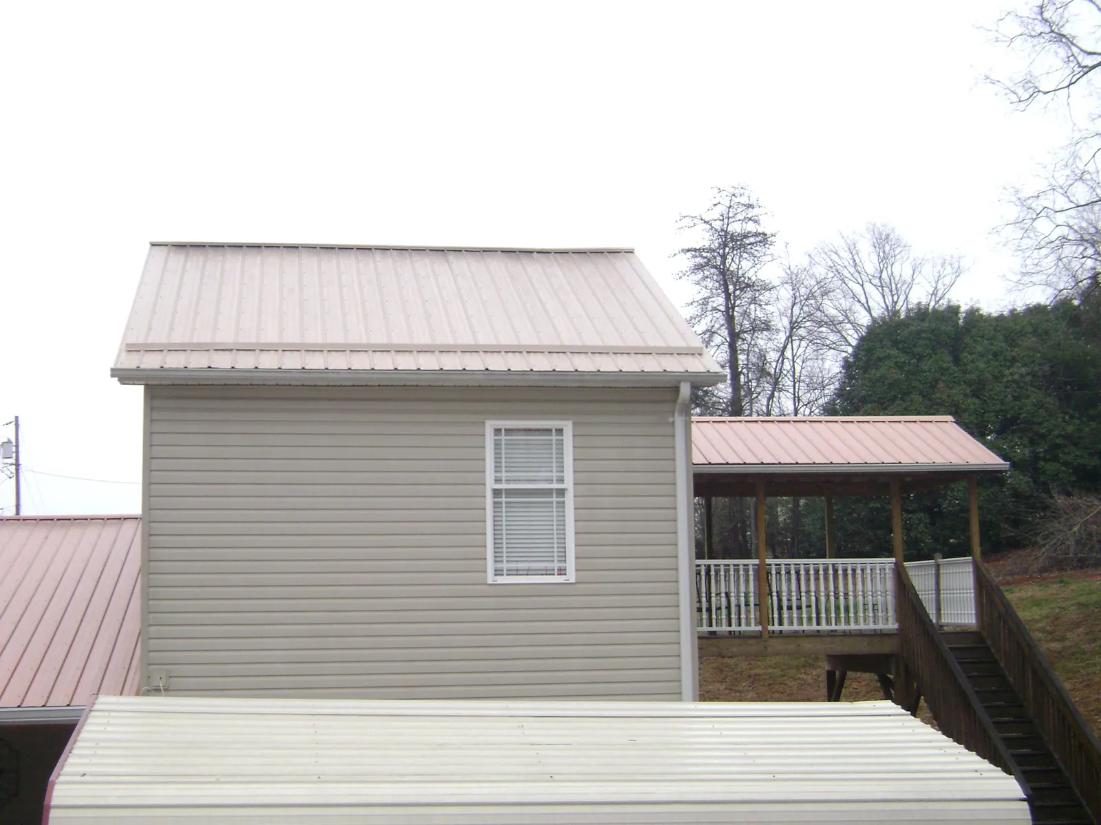 Tan metal roofs on a two story addition and attached porch, from a Roof Replacement job in Tigrett