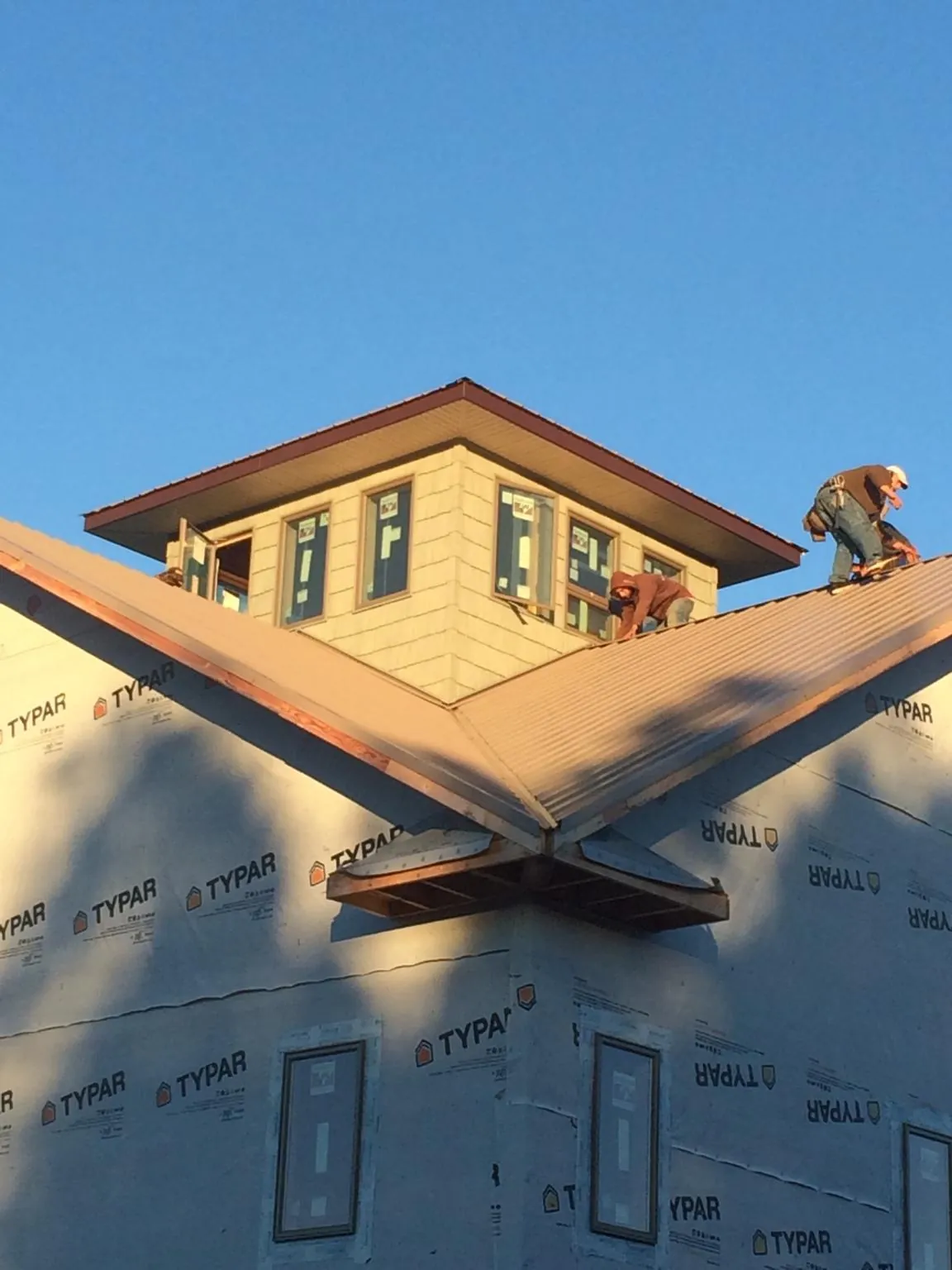 Roofers working around a rooftop cupola on a new metal roof at sunset — Roof Waterproofing in Tigrett by Roofing Brothers